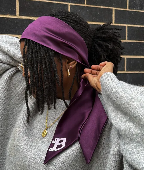 Model tying the Braid silk scarf around their locs
